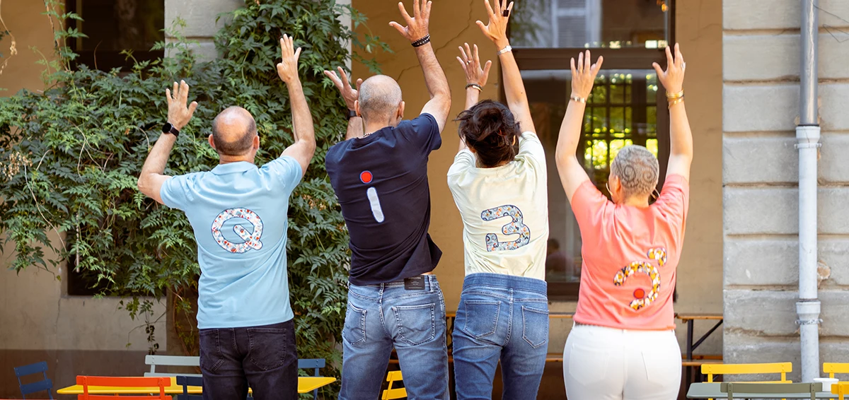 Quatre fondateurs d’une marque de vêtements thérapeutiques, de dos et se donnant la main, portant des t-shirts avec les lettres Qi-Bô.